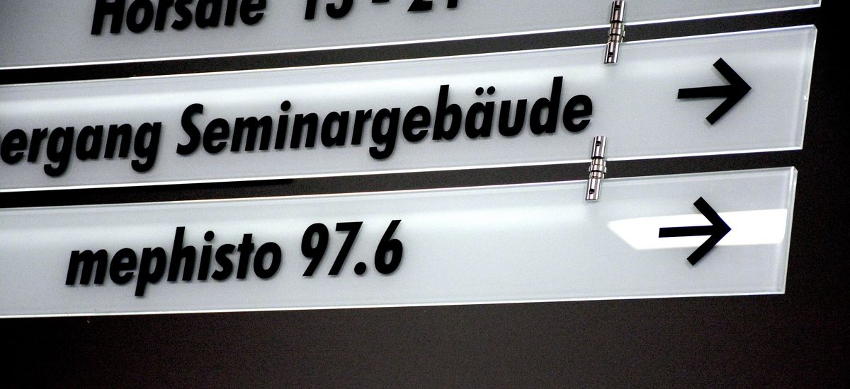 Das Foto zeigt einen Wegweiser im Hörsaalgebäude mit dem Schriftaufzug "mephisto 97.6". Foto: Joris Bartsch